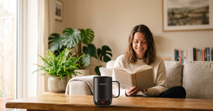 Woman reading on a sofa with a VSITOO S3 Pro self-heating coffee mug on the coffee table