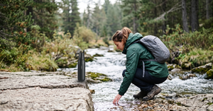 VSITOO S2 filtered water bottle standing on a rock beside a mountain stream
